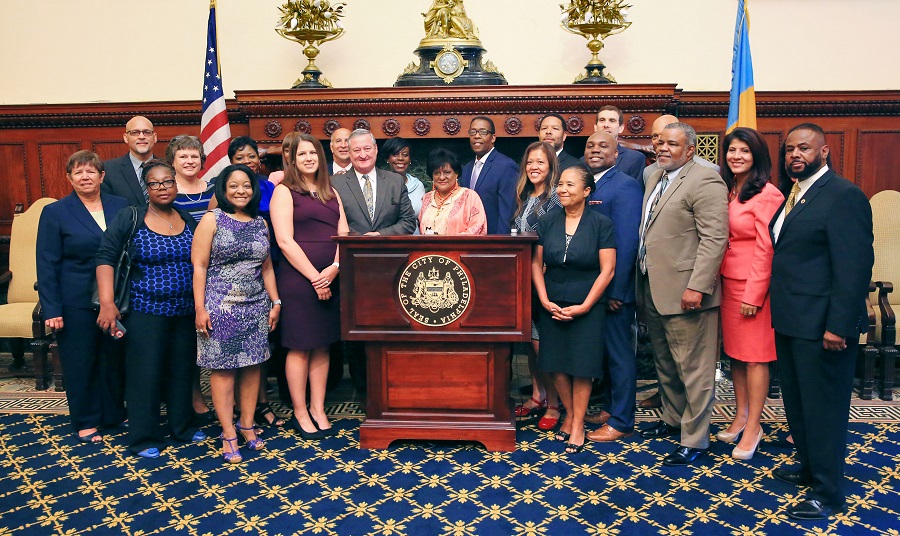 Mayor Kenney surrounded by people smiling at City Hall.