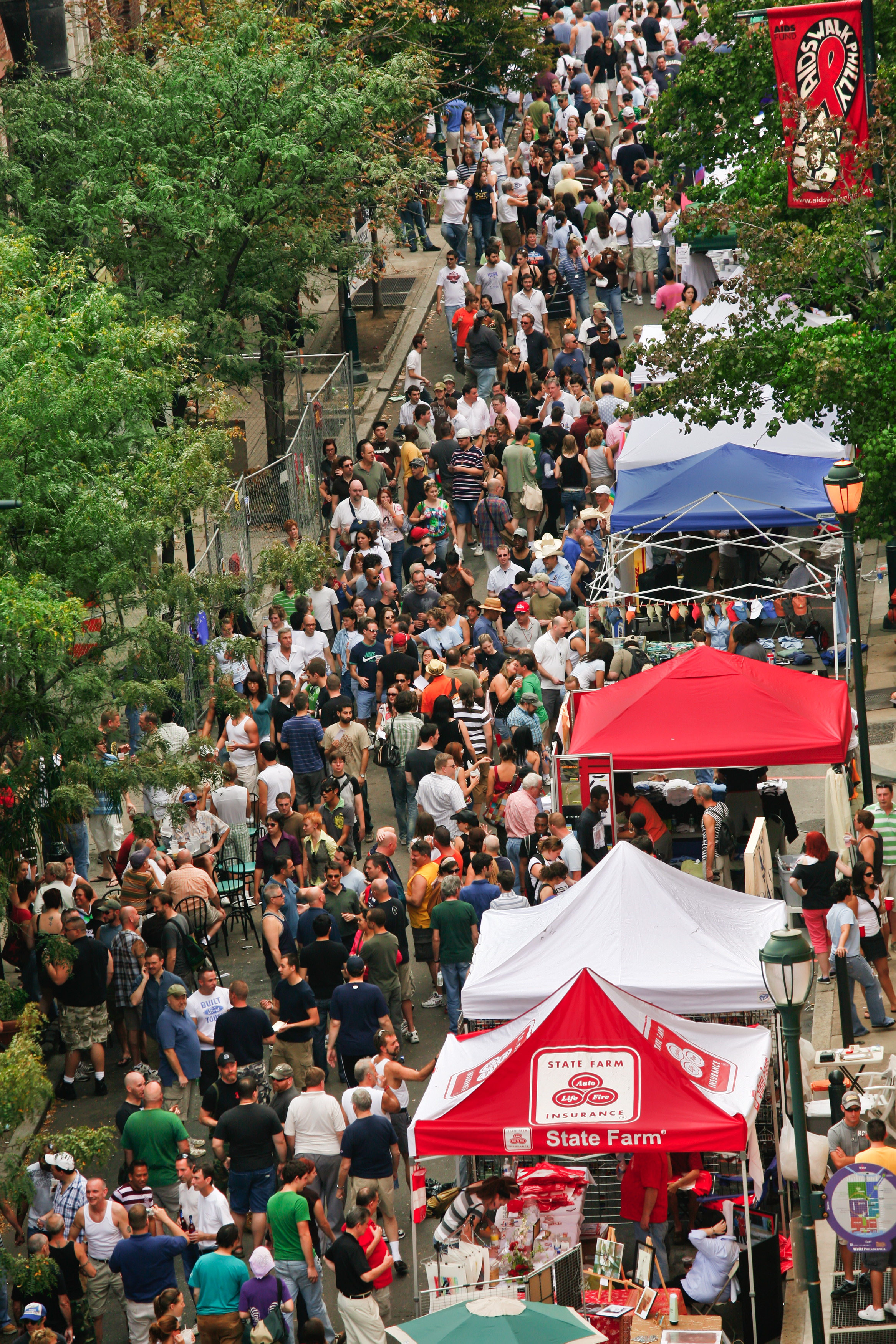 A street is closed to cars and filled with pedestrians and vendor booths in the city's Gayborhood.