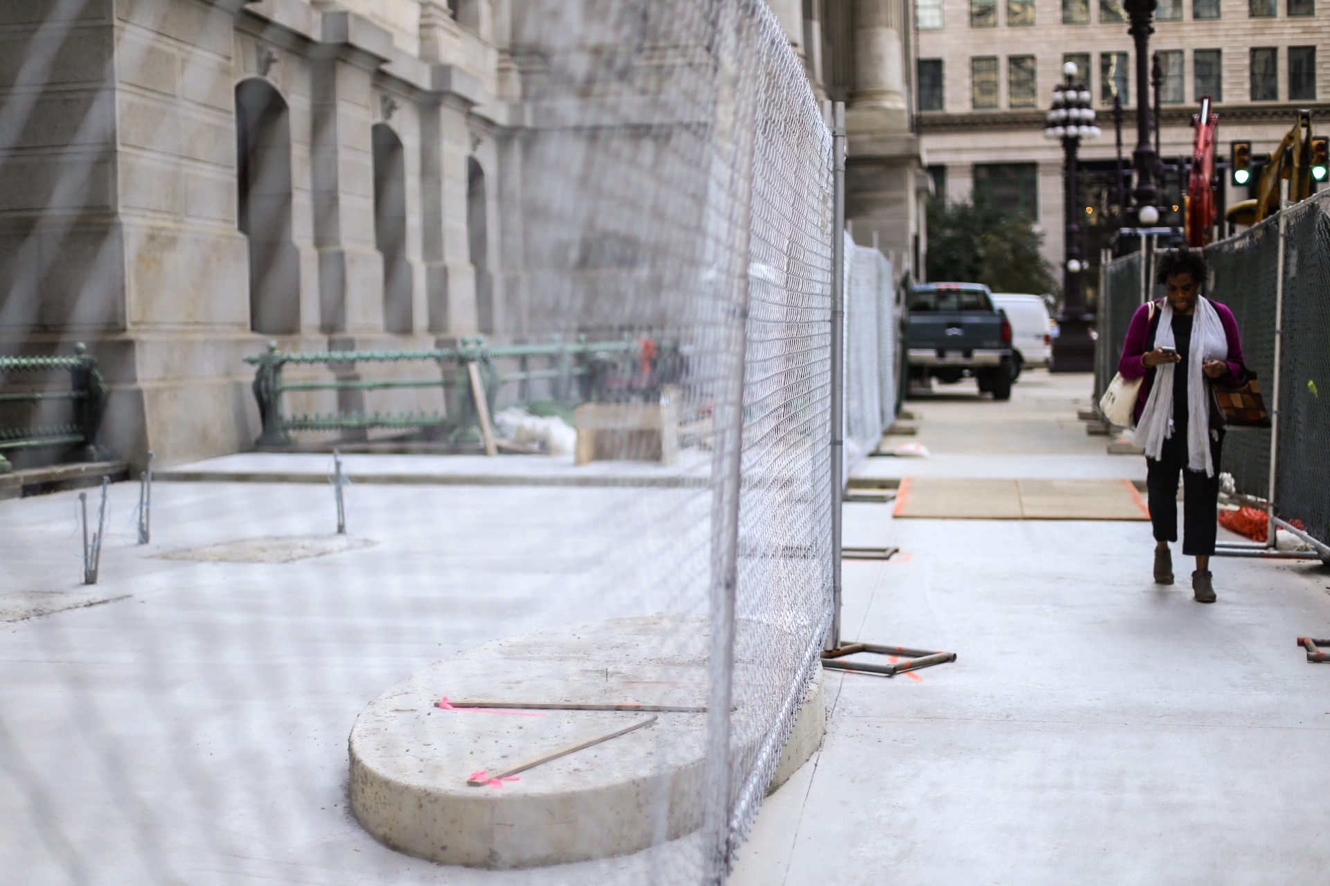 A woman walks by the construction site where the Catto statue will sit.