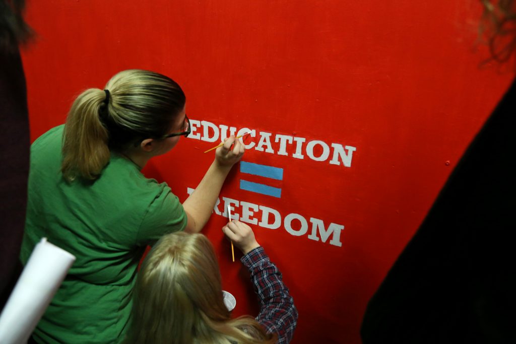 Volunteers paint inspirational messages on the walls of Harding Middle School in Frankford