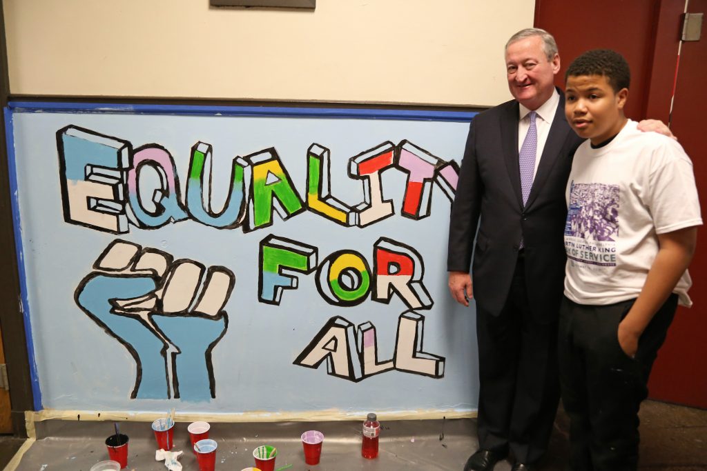 Mayor Kenney poses with a student who helped design the painting pictured on the wall. 