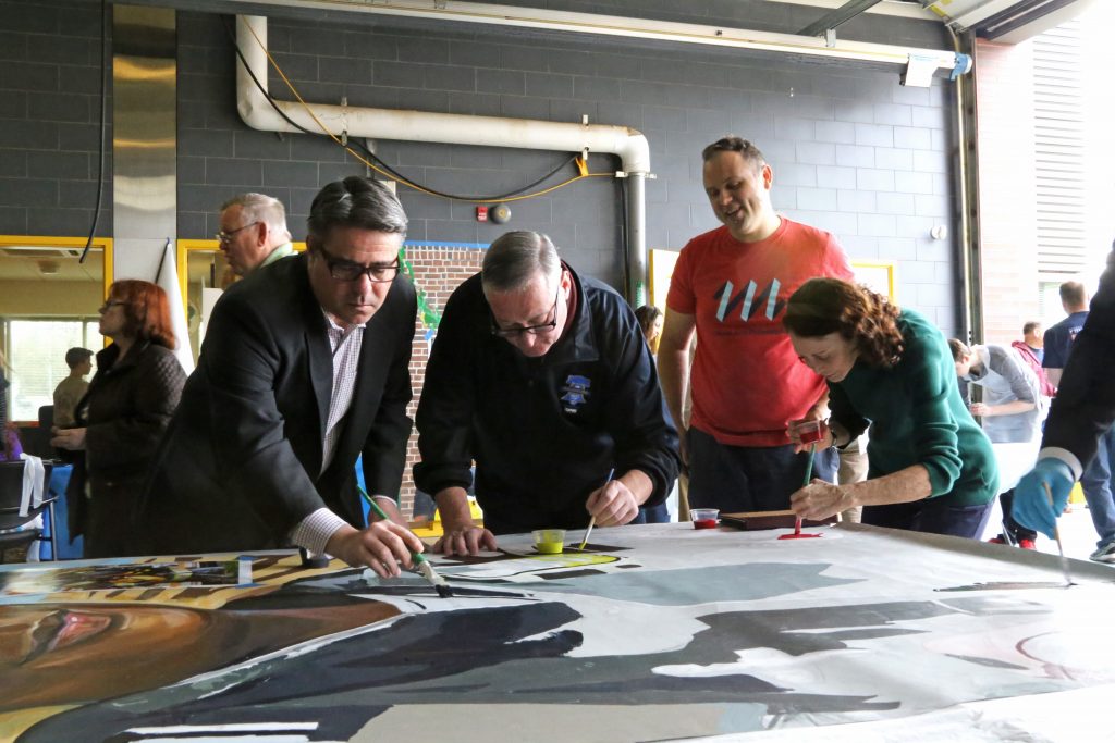 Mayor Kenney, Councilman Bobby Henon, and Mural Arts Director Jane Golden help complete the mural honoring fallen firefighters Joyce Craig and James Hynes, during a mural paint day.