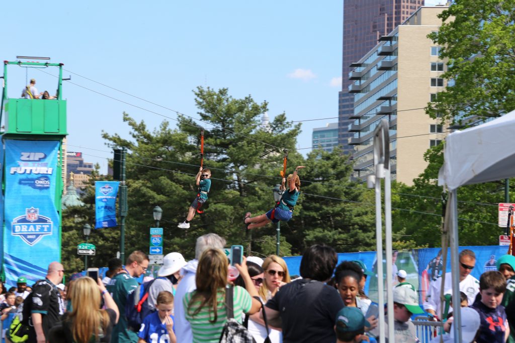 Attendees of the NFL Draft Experience ride on a 100-yard zip line on April 28.