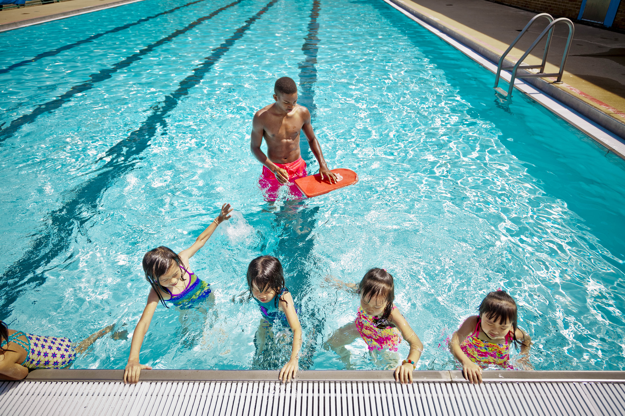 A Parks and Rec lifeguard wades into water supervising children during a swim test.