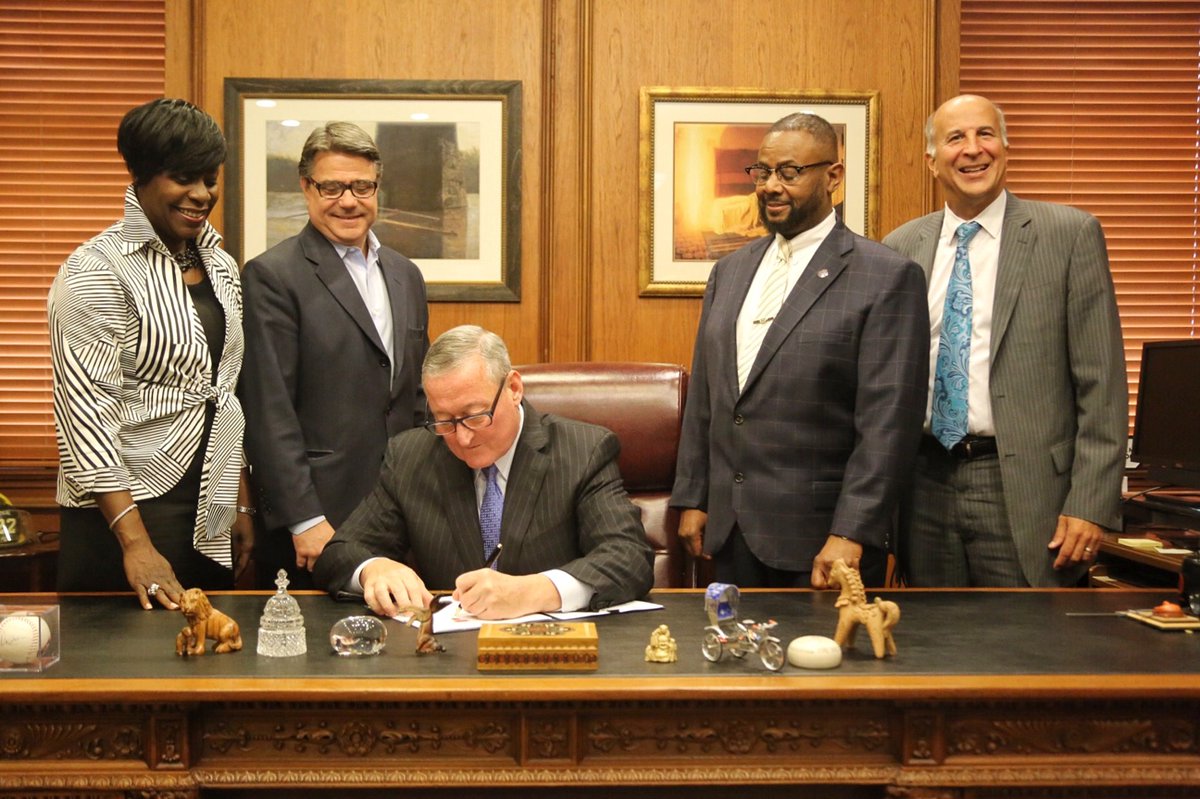 Mayor Kenney sits at his desk and is flanked by four members of City Council.
