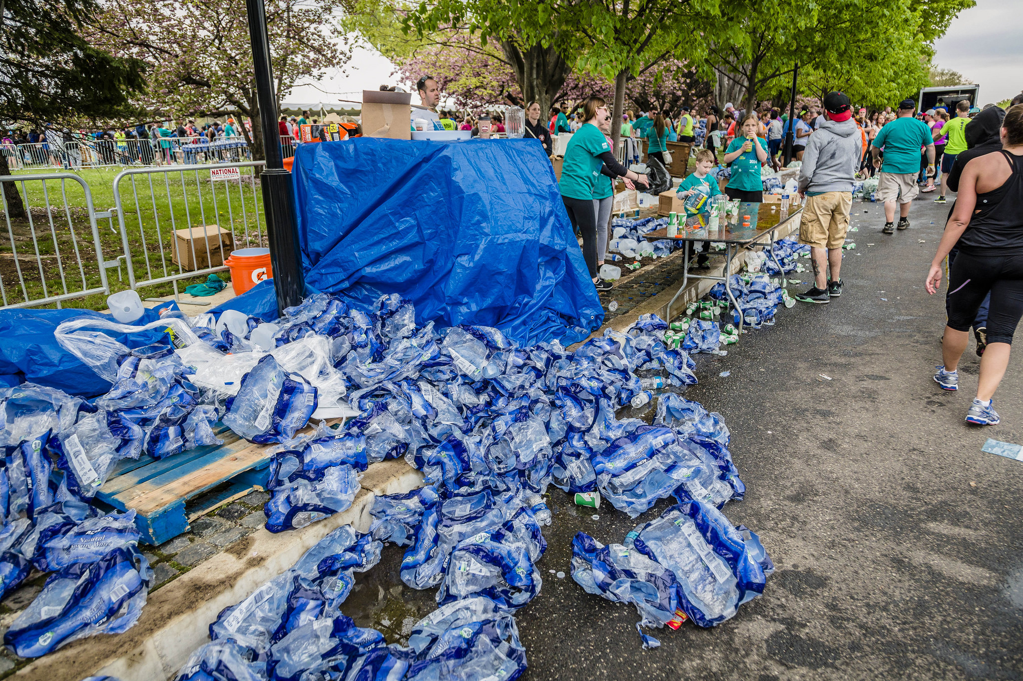 Hundreds of plastic packages and cups are piled along a curb after having been swept up.