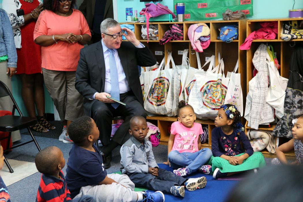 Mayor Kenney lifts his glasses and exchanges glances with a pre-K student during reading time.