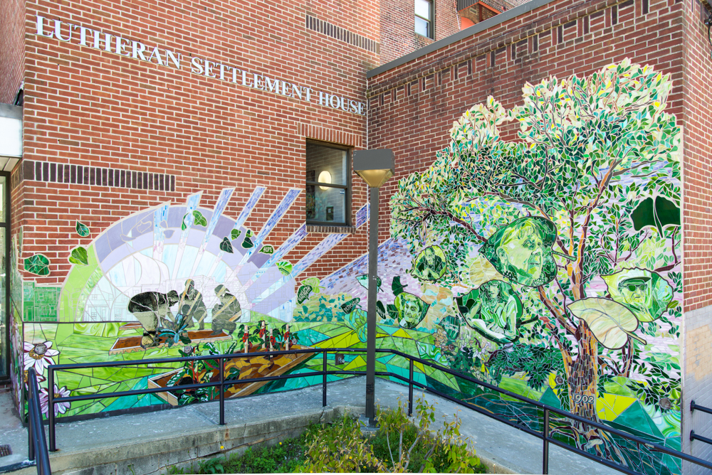 A vibrant mural depicting a purple sunrise and lush trees and plants growing as figures of people plant seeds.