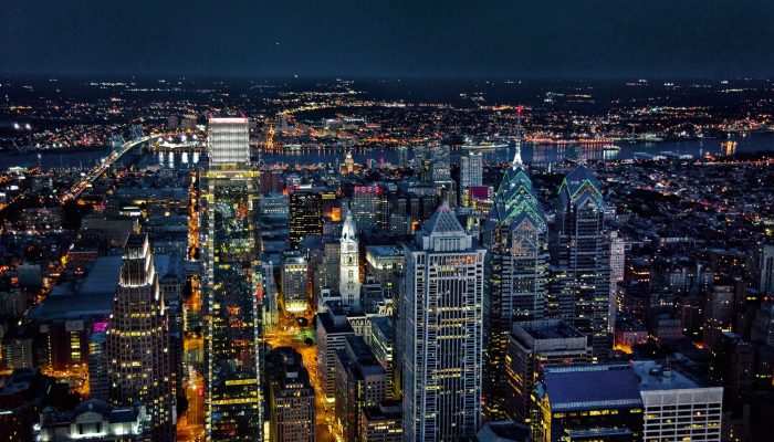 Glass skyscrapers sparkle at night as city lights twinkle and reflect off of them. The city is alight with life and the pictures evokes excitement and technology.