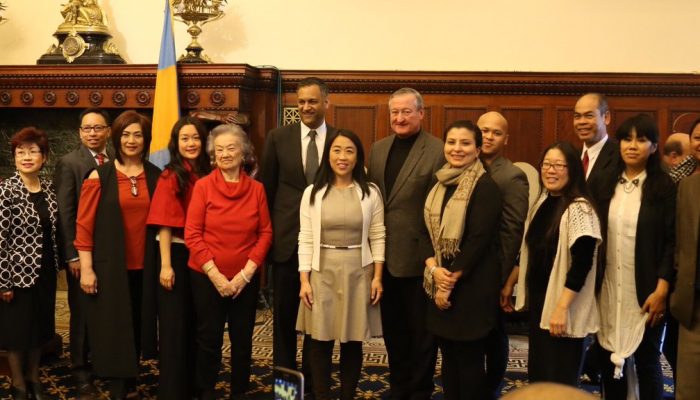 Mayor Kenney stands in the center of several local Asian American leaders at City Hall. There are portraits of all the mayors in Philadelphia history behind them.