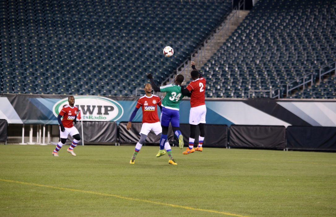 Soccer players from Sierra Leone and Liberia play in the Unity Cup Championship. One player from each team jumps for control of the ball while two others stand at the ready.