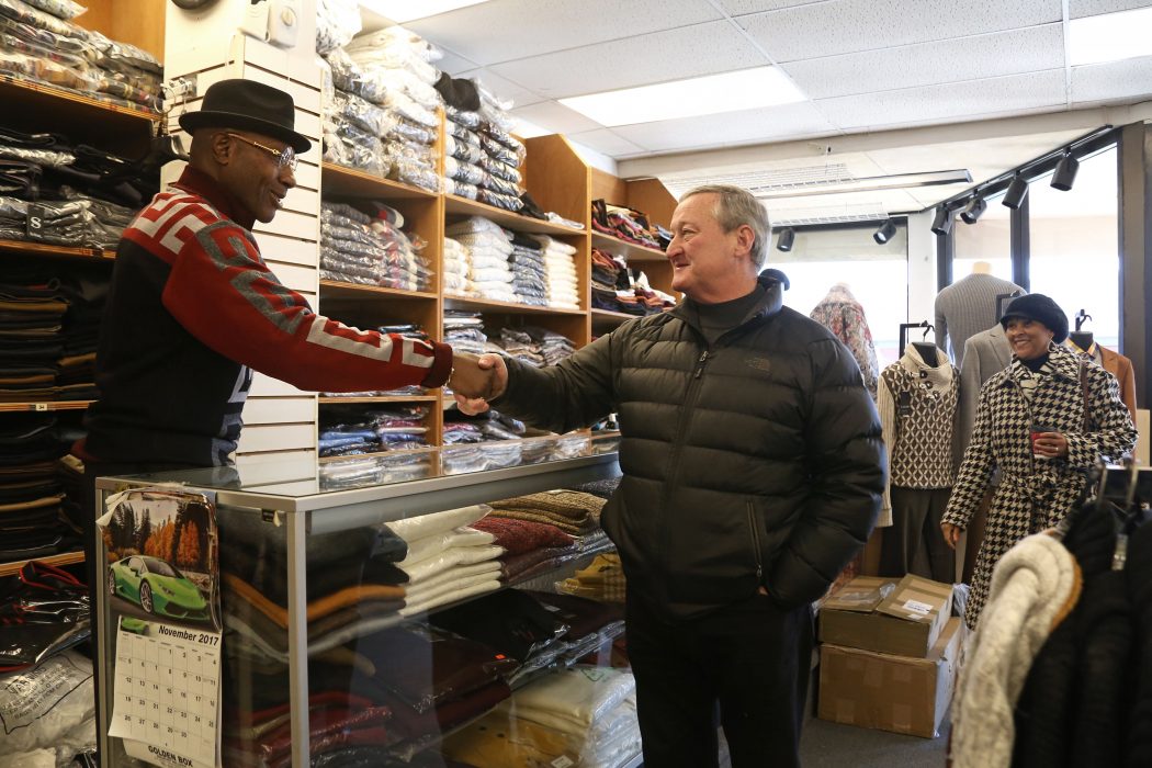 Mayor Kenney happily shakes hands with an smiling employee of a local clothing store.