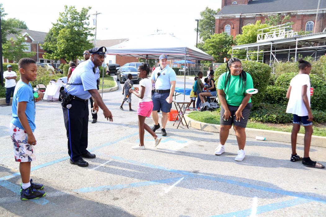 Philadelphia Police officers and community members play a ring toss game during National Night Out on August 1