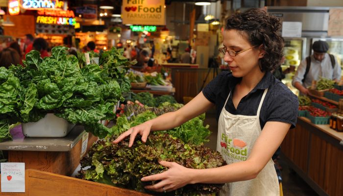 A clerk at Reading Terminal Market's Fair Food Farmstand makes sure the stands are packed with fresh produce.