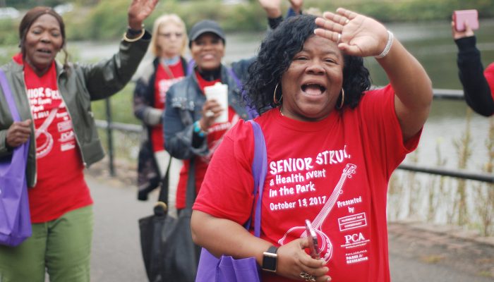 A group of women smile and wave as they participate in the Senior Strut.