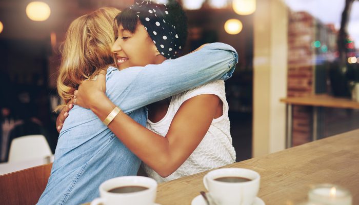 Two women embrace at a coffee shop.