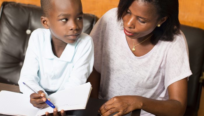 A mother helps her son with his homework.