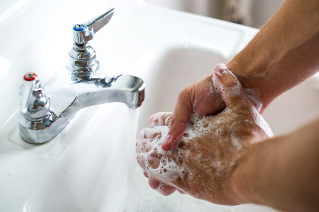 Hands getting washed in a sink