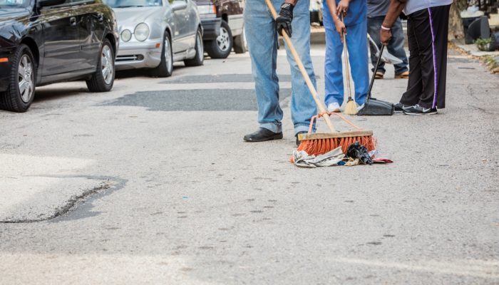 Residents sweeping litter on a city street.
