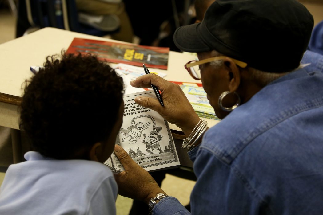 A Philly Reading Coaches volunteer reads to a student.