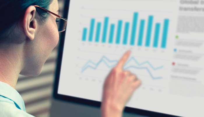 Woman looks at graphs on a computer monitor.