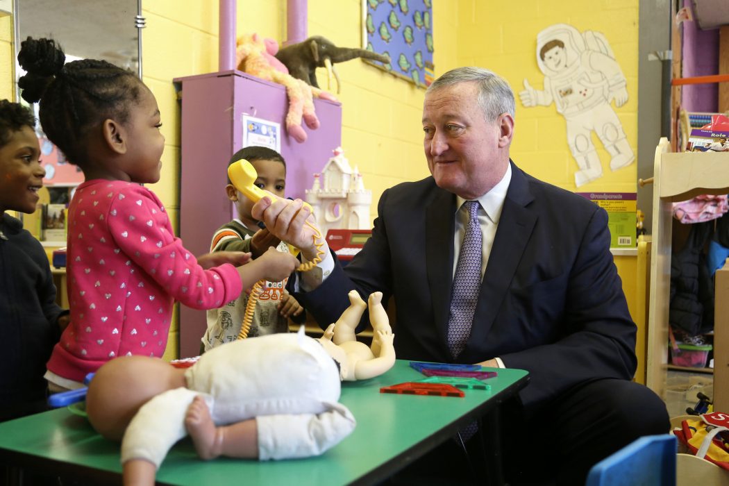 Mayor playfully handing a toy phone to a PHLpreK student.