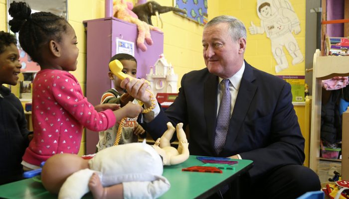 Mayor playfully handing a toy phone to a PHLpreK student.
