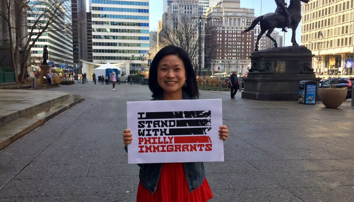 Woman holding Immigrant Heritage Month sign