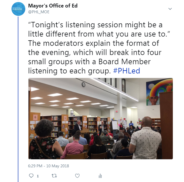 Moderators speak before group of seated small groups at the listening session