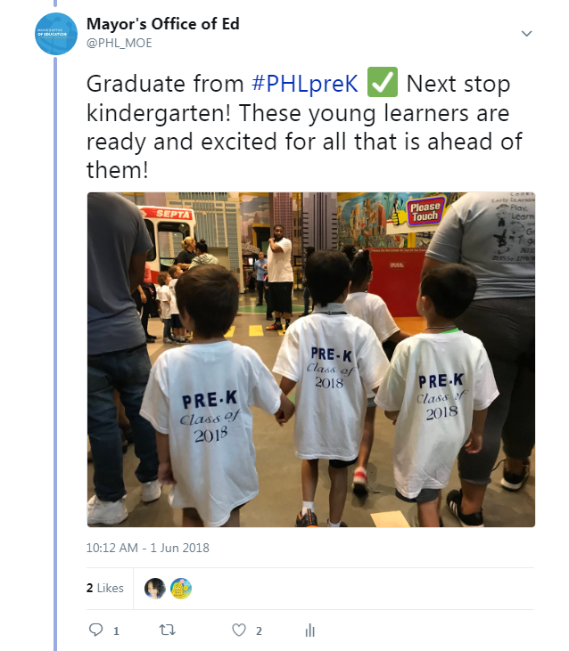 Three PHLpreK graduates wearing shirts that read “Pre-K Class of 2018” hold hands and walk through the Please Touch Museum