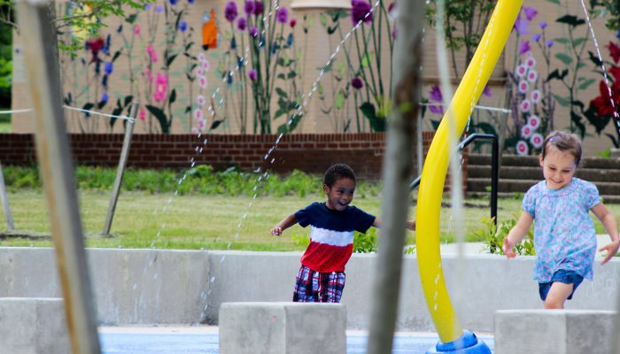 Young child running through sprayground at park