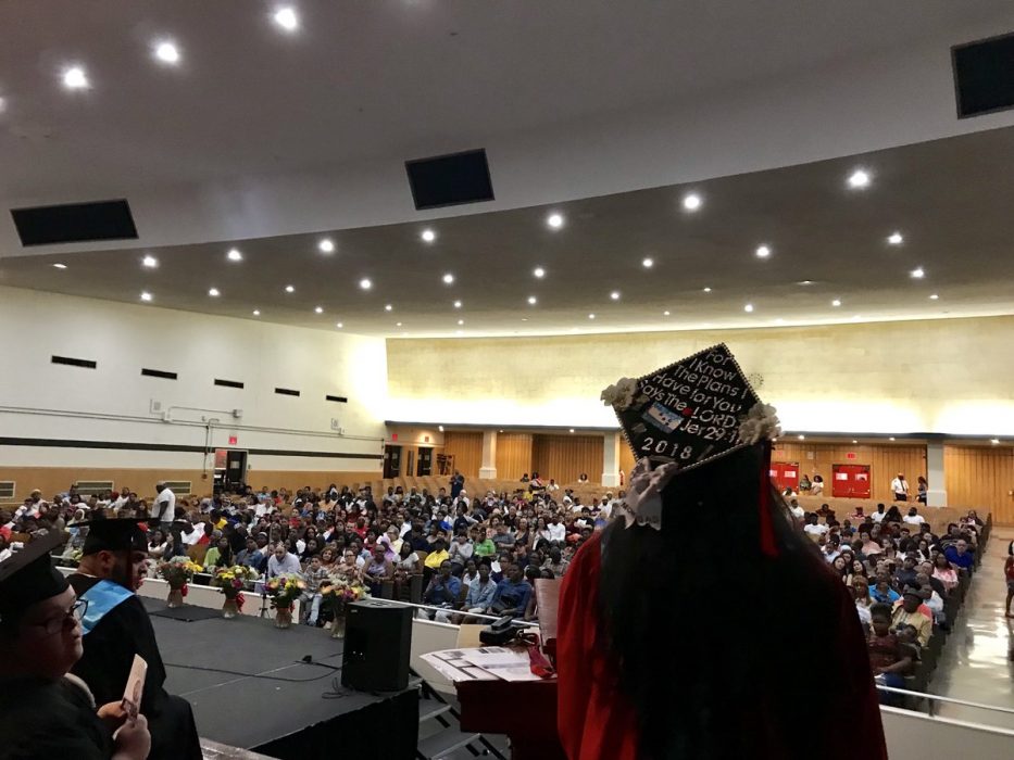A graduate stands on stage delivering a captivating speech overlooking the crowd.