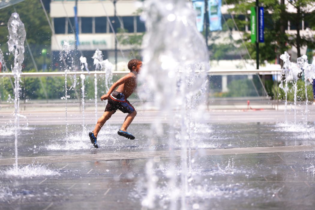 A happy little boy running through the Dilworth Park fountains on a hot summer day.