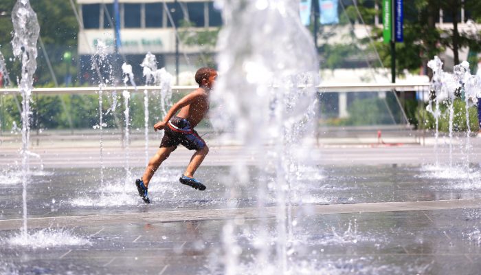 A happy little boy running through the Dilworth Park fountains on a hot summer day.
