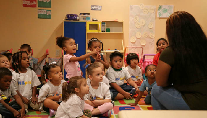 Philadelphia school children sit on a rug and listen to their teacher read a story