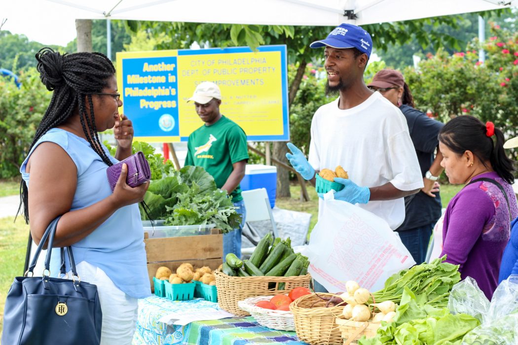 A woman buys produce at a farmers' market