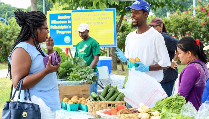 A woman buys produce at a farmers' market