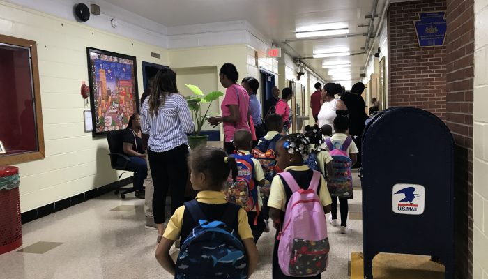 Students at Edward Gideon Elementary School walk to class with backpacks on.