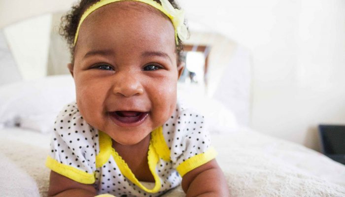 Một em bé đeo băng đô màu vàng mỉm cười