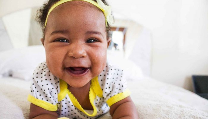 A baby wearing a yellow headband smiles