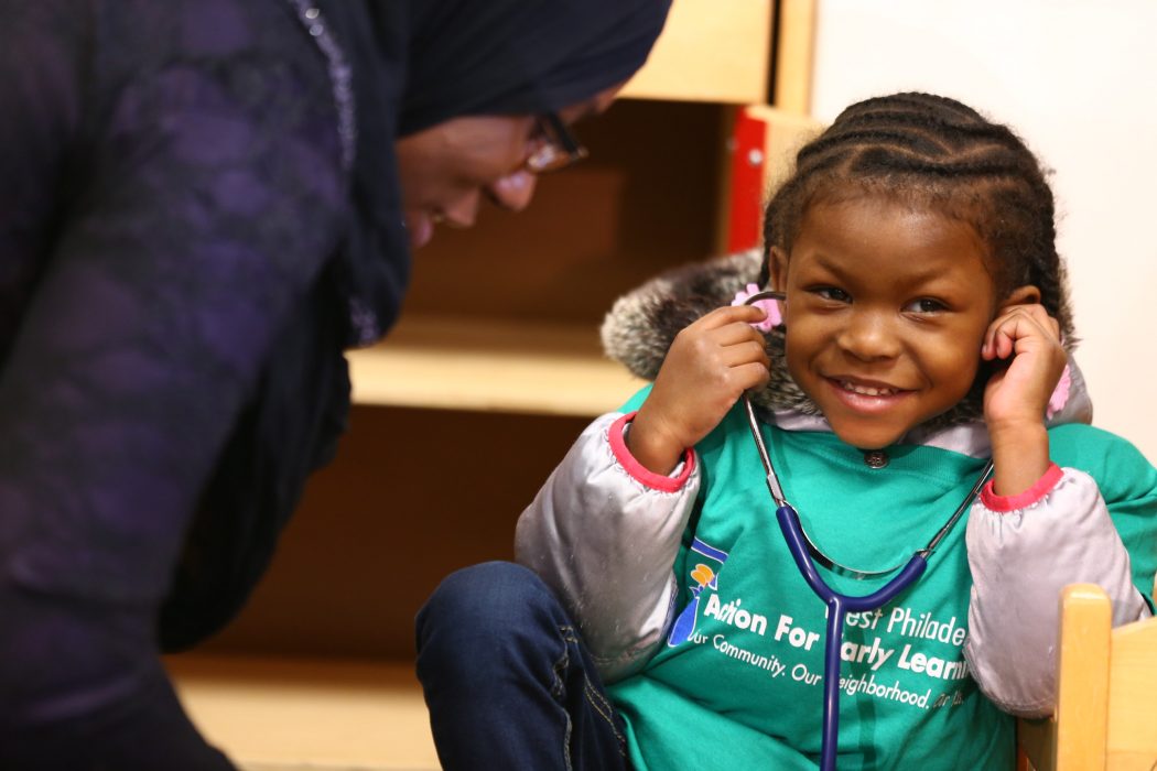 young girl smiling and listening to a stethoscope