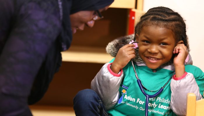 young girl smiling and listening to a stethoscope