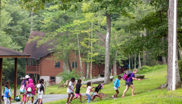 A group of girl campers walk with their counselor