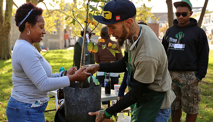 Two people hold a tree in a bag at a TreePhilly event.