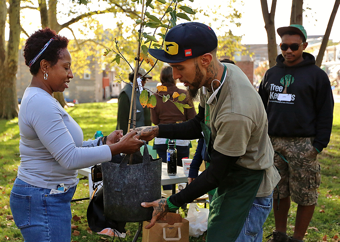 Two people hold a tree in a bag at a TreePhilly event.