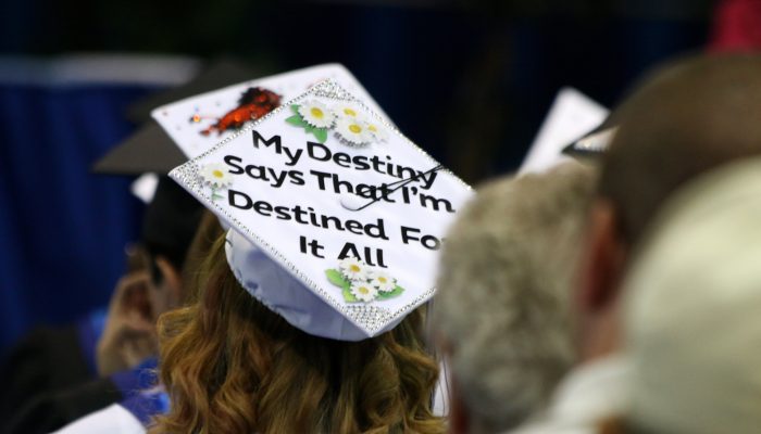 woman wearing a graduation cap that says "my destiny says that I'm destined for it all"
