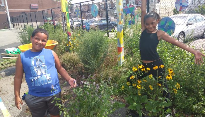 Two Cramp Elementary students pose in the new garden surrounded by yellow and purple flowers they planted