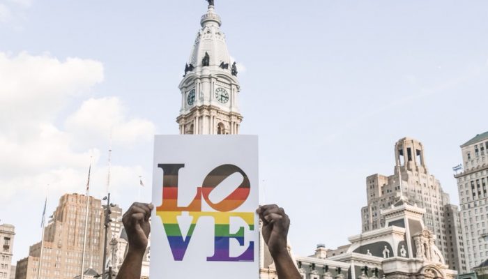 person holding a sign that says love in front of philadelphia city hall.
