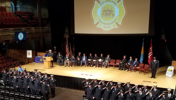 Firefighters saluting in front of stage