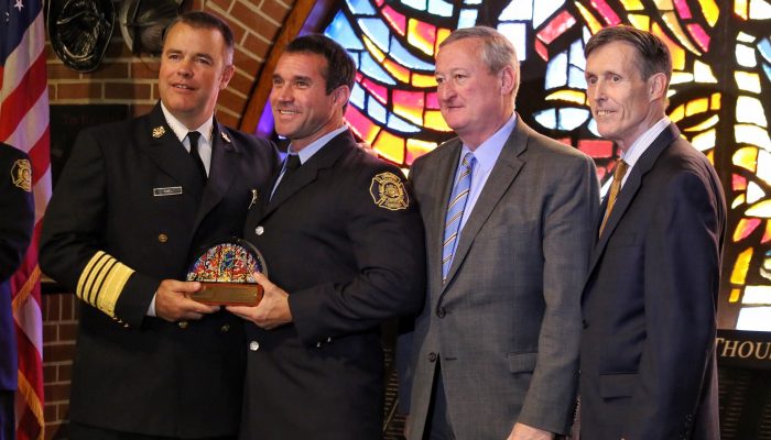 Firefighter holding award with dignitaries